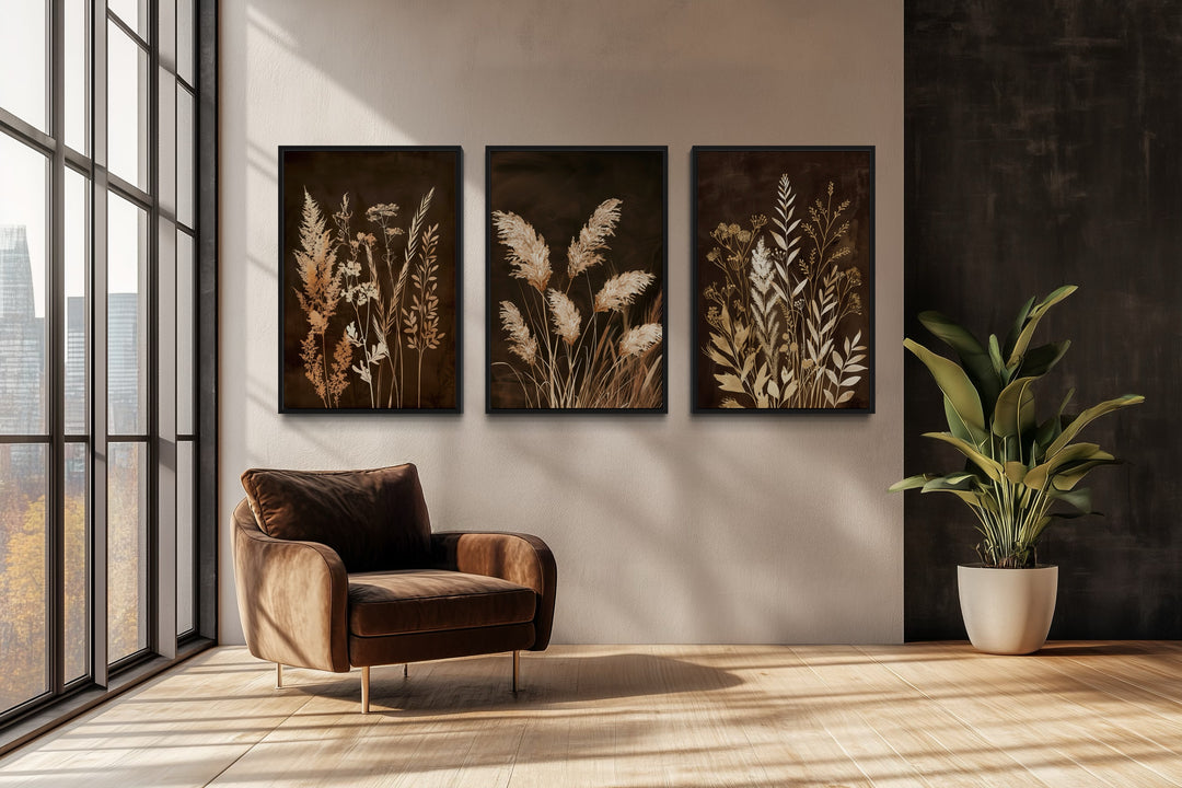 Set of 3 brown and beige boho botanical grass canvas prints on a wall above a brown velvet chair.