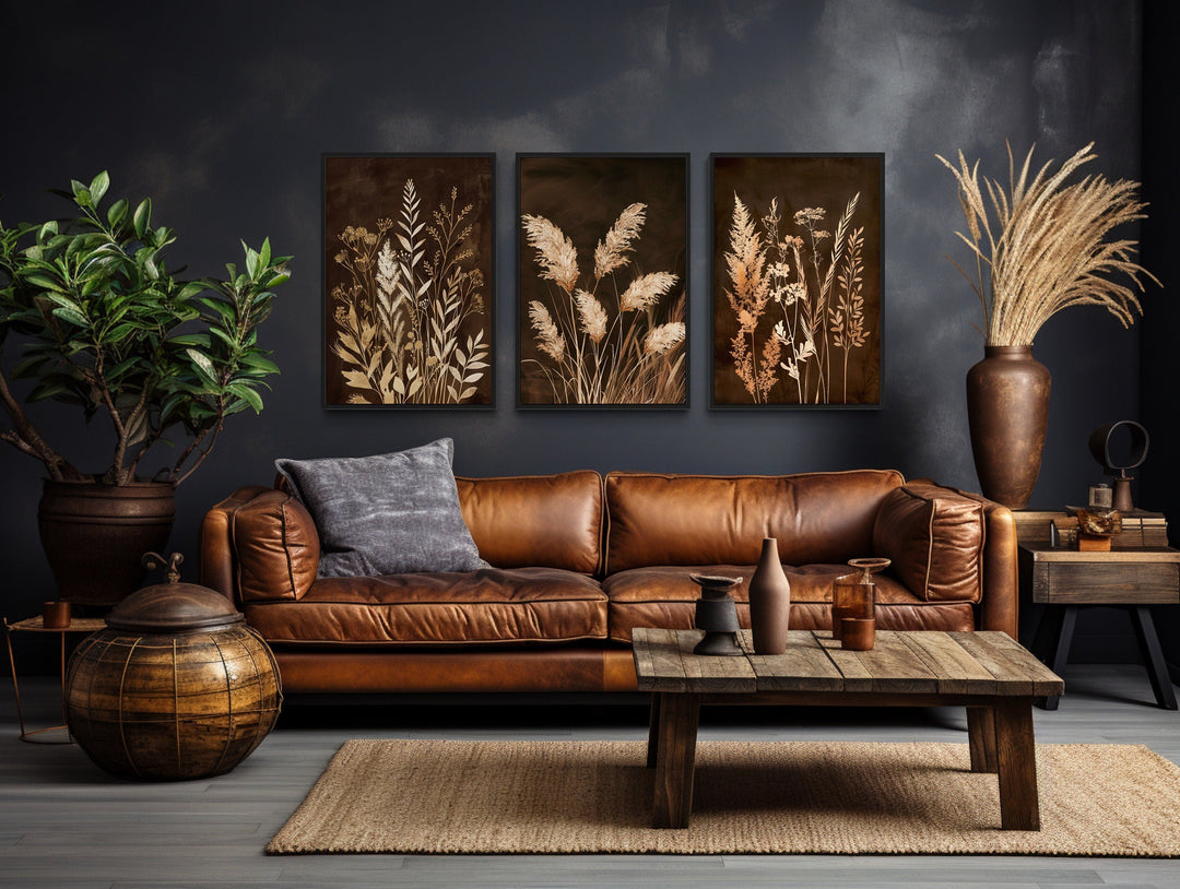 Set of 3 brown and beige boho canvas wall art featuring botanical grass in a dark living room.