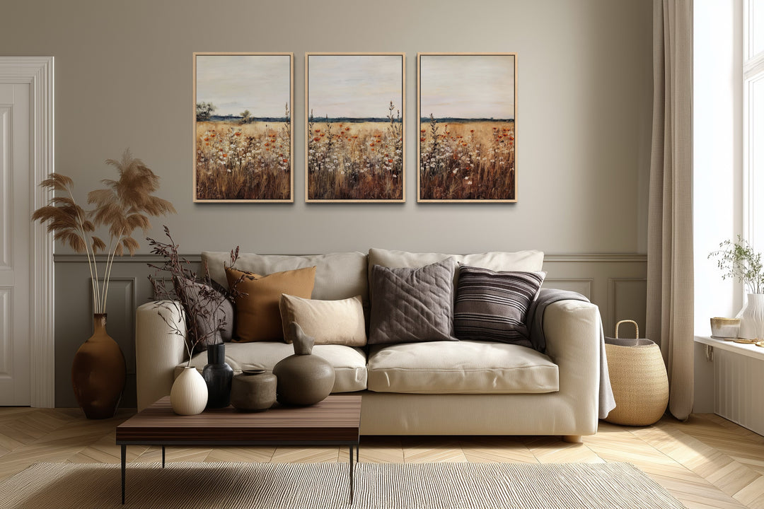 Set of 3 framed canvas prints featuring a rustic wildflower field above a neutral sofa.