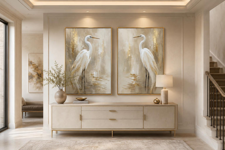 Set of 2 white egret canvas wall art prints with golden water accents in gold frames.