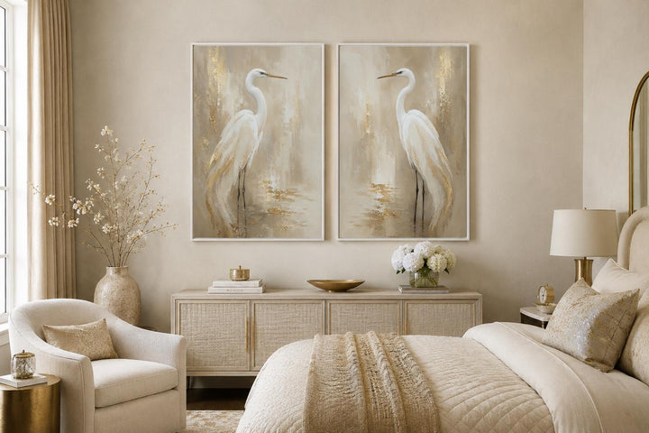 Set of 2 white egret canvas wall art prints with gold accents in a neutral bedroom.