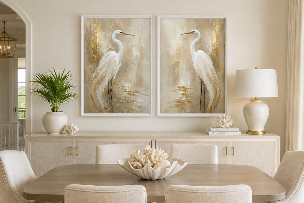 Set of 2 white egret canvas wall art prints with gold accents above a dining room sideboard.