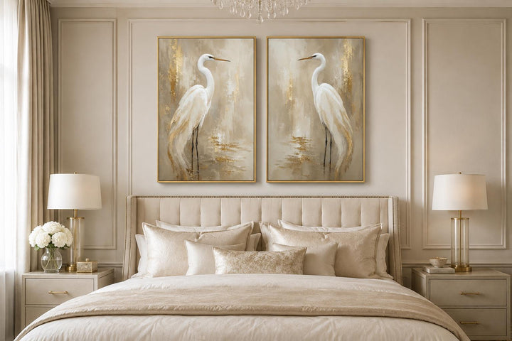 Set of 2 white egret canvas wall art with gold accents hung above a neutral upholstered bed.