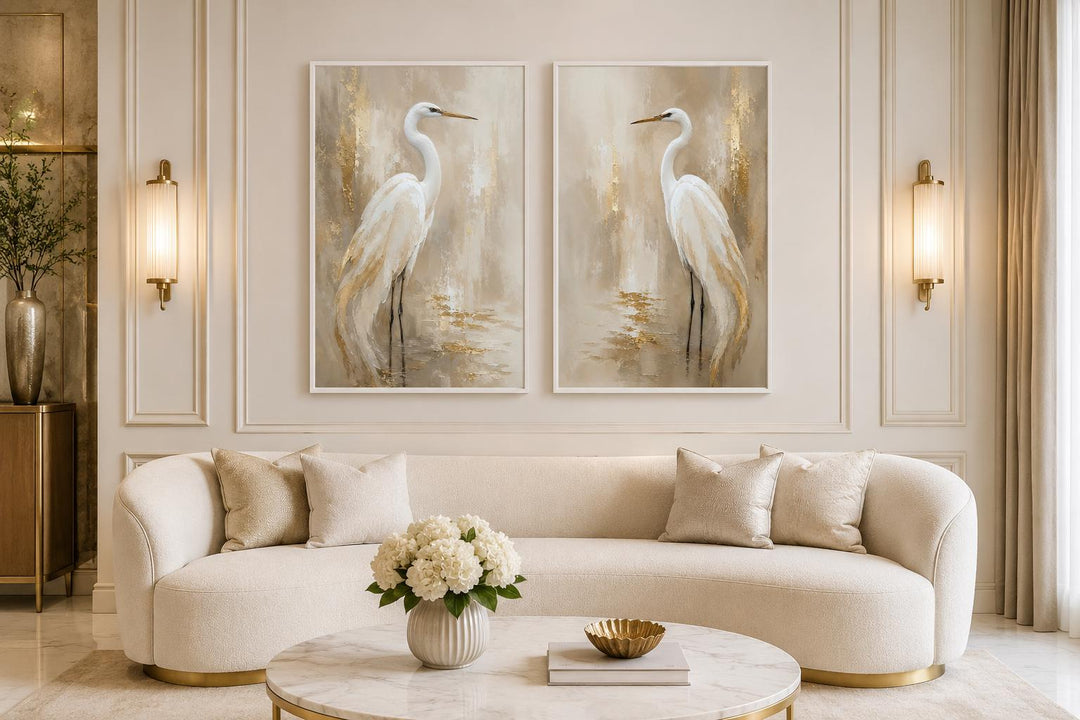 Set of 2 white egret canvas wall art prints with metallic gold accents in a neutral living room.