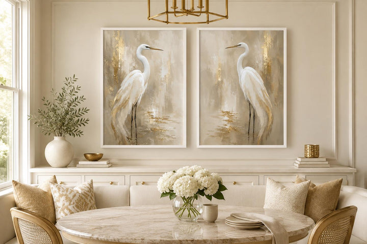 Set of 2 white egret canvas wall art prints with golden water accents in a neutral dining room.