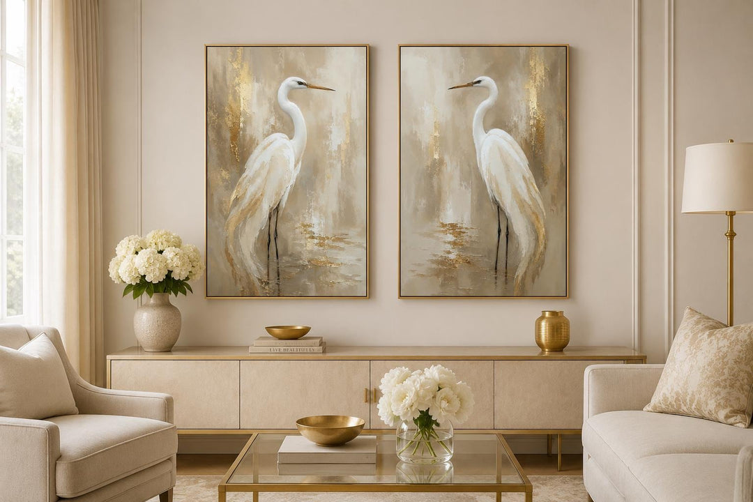 Set of 2 white egret canvas wall art with gold accents in a neutral living room.