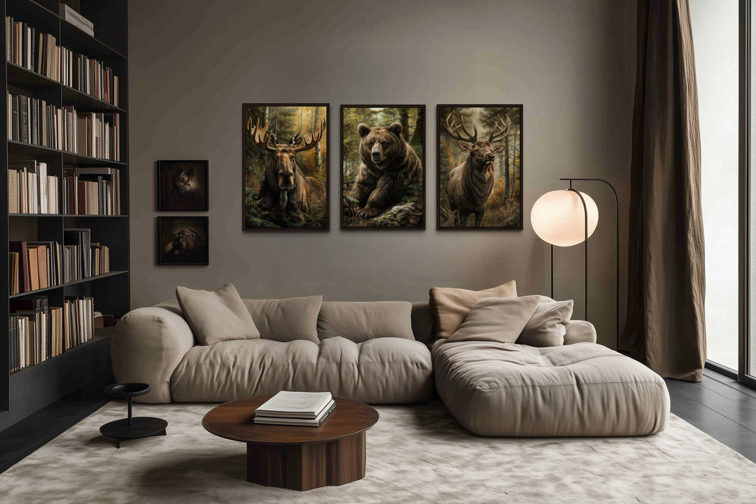 Set of 3 framed canvas paintings of a moose, bear, and elk hanging above a modern beige sofa.