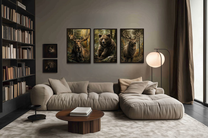 Set of 3 framed canvas paintings of a moose, bear, and elk hanging above a modern beige sofa.