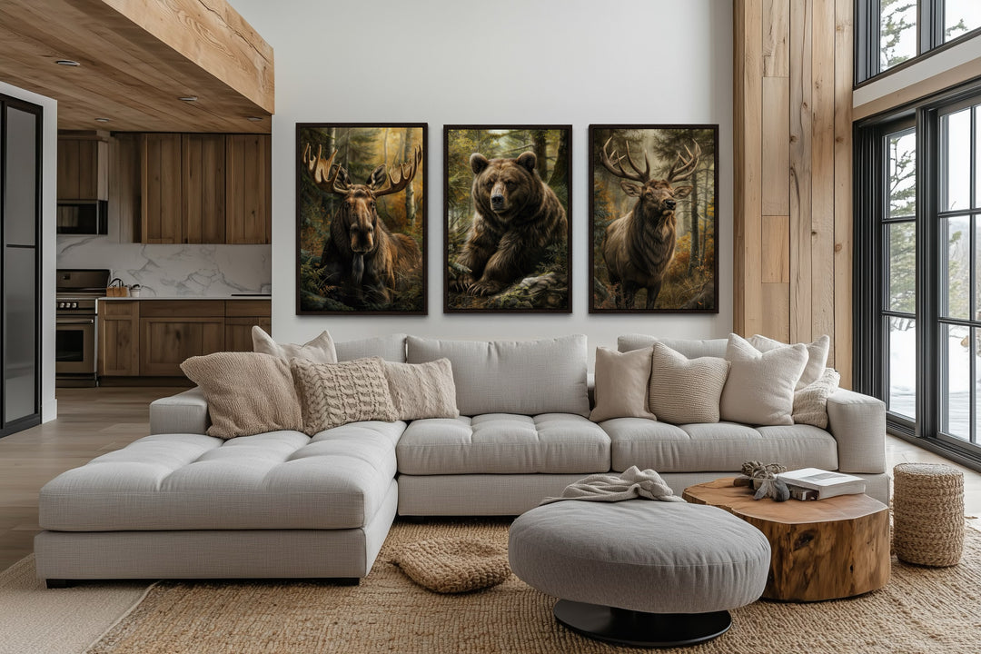 Set of 3 framed canvas paintings of a moose, bear, and elk hanging above a modern sectional sofa.