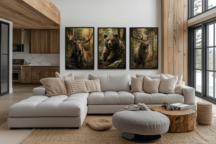 Set of 3 framed canvas paintings of a moose, bear, and elk hanging above a modern sectional sofa.