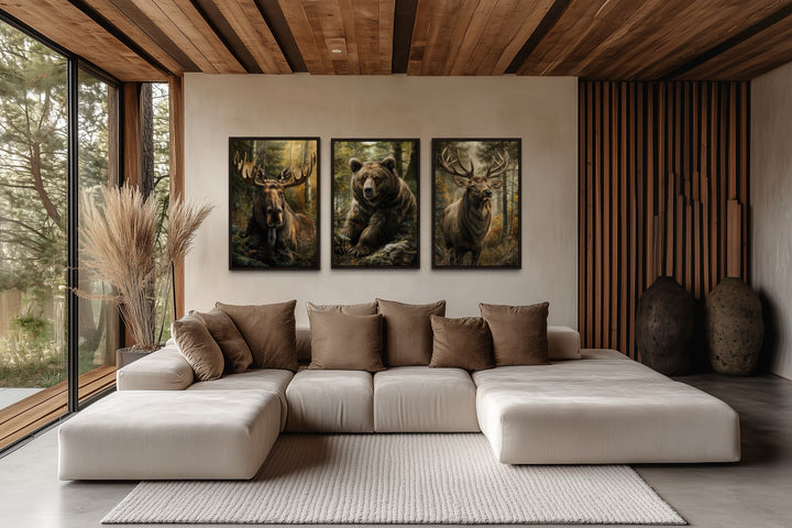 Set of 3 framed canvas paintings of a moose, bear, and elk in a rustic living room setting.