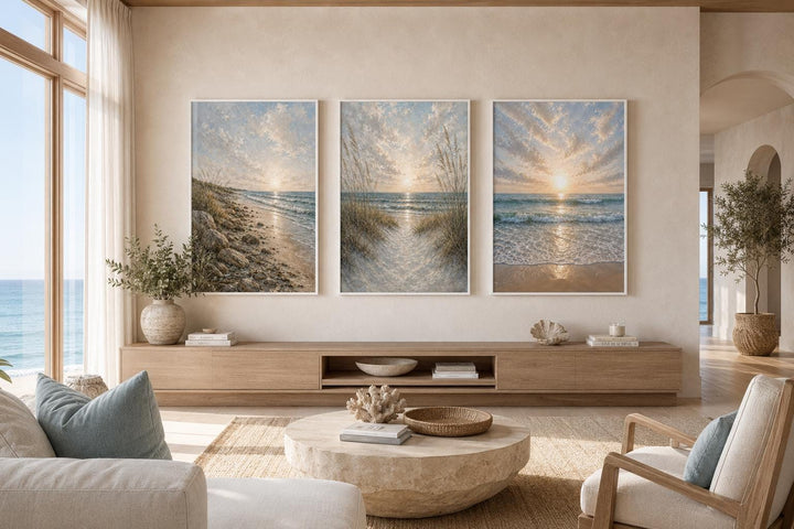 Set of 3 vertical beach sunset paintings with dunes and waves in a coastal living room.