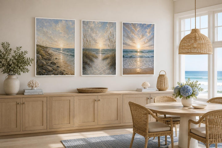 Set of 3 vertical beach sunset paintings with dunes and waves above a wooden sideboard.