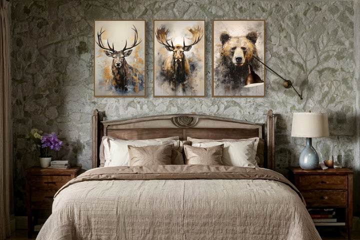 Set of 3 wildlife canvas prints featuring a bear, moose, and elk above a bed in a rustic room.