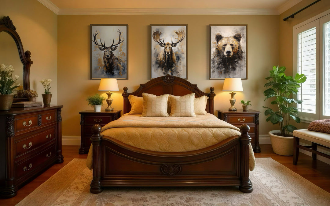 Set of 3 framed wildlife canvas prints featuring a bear, moose, and elk above a bed in a cabin.