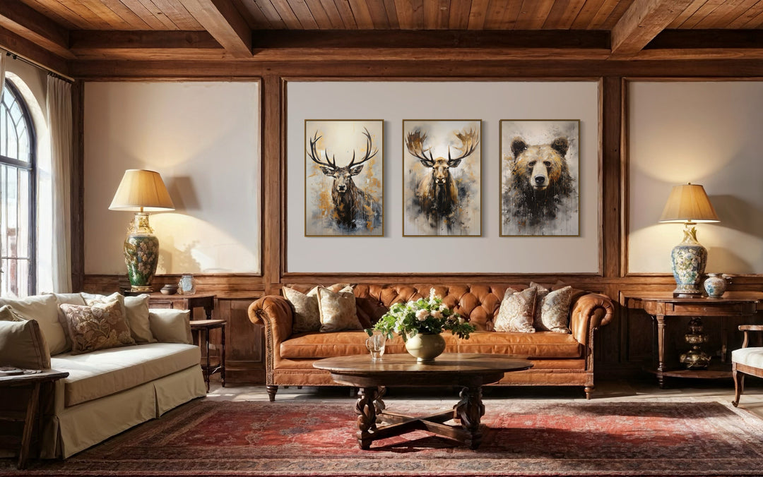 Set of 3 framed wildlife canvas prints featuring an elk, moose, and bear above a leather sofa.