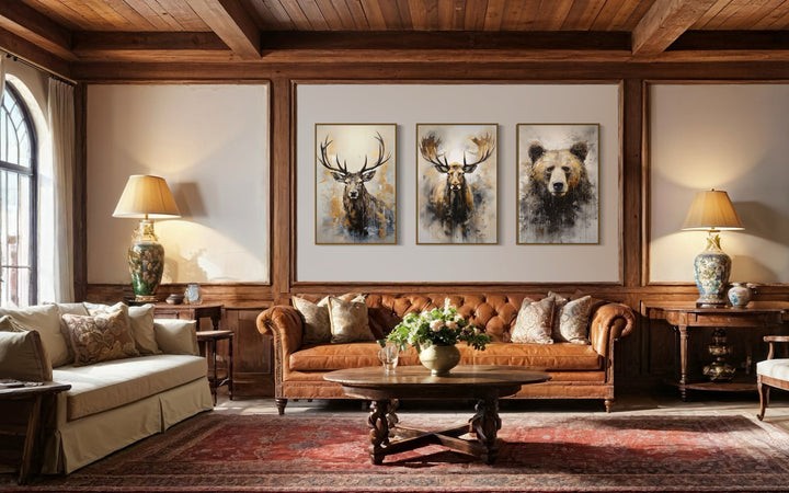 Set of 3 framed wildlife canvas prints featuring an elk, moose, and bear above a leather sofa.