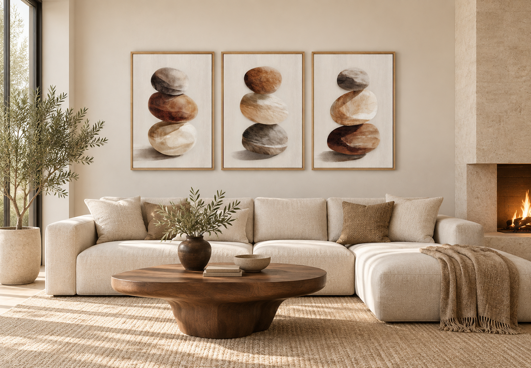 Set of 3 minimalist canvas prints featuring stacked stones in neutral tones above a beige sofa.