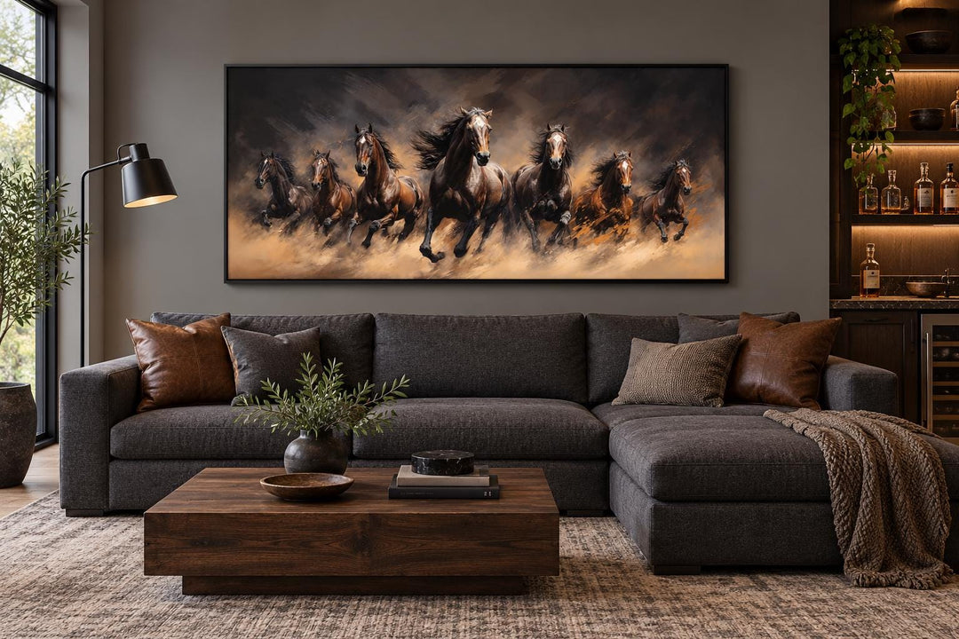 Seven wild horses galloping through swirling dust framed canvas wall art above a dark gray sofa.