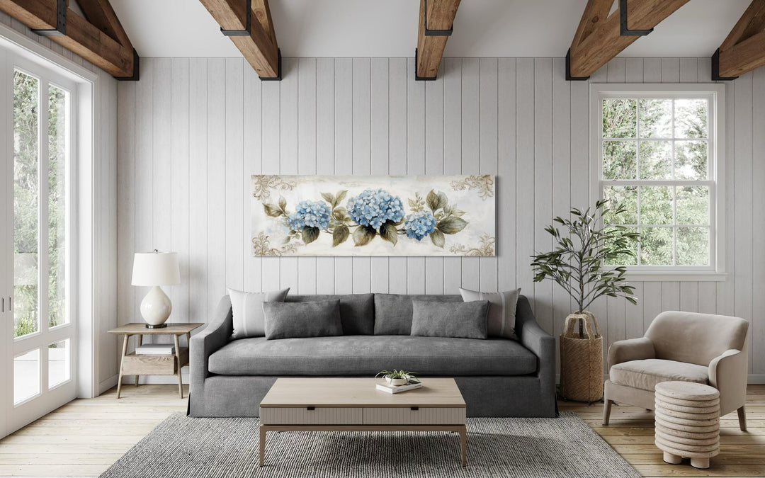 Shabby chic long horizontal canvas wall art featuring blue hydrangea blooms on a neutral wall.