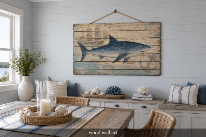 Distressed wood panel wall art featuring a blue shark, vintage ship, and anchor in a coastal room.
