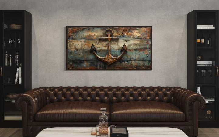 Nautical framed canvas wall art featuring a ship's anchor painted on weathered wood above a sofa.