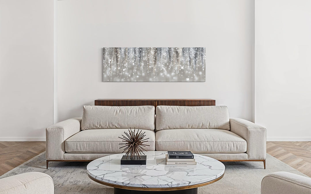 Modern horizontal canvas print featuring abstract silver and beige rain over a neutral sofa.