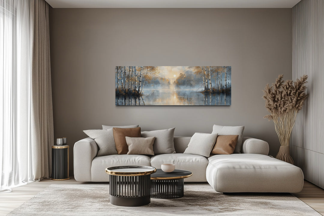 Panoramic wall art of a misty silver birch forest over a living room sofa.
