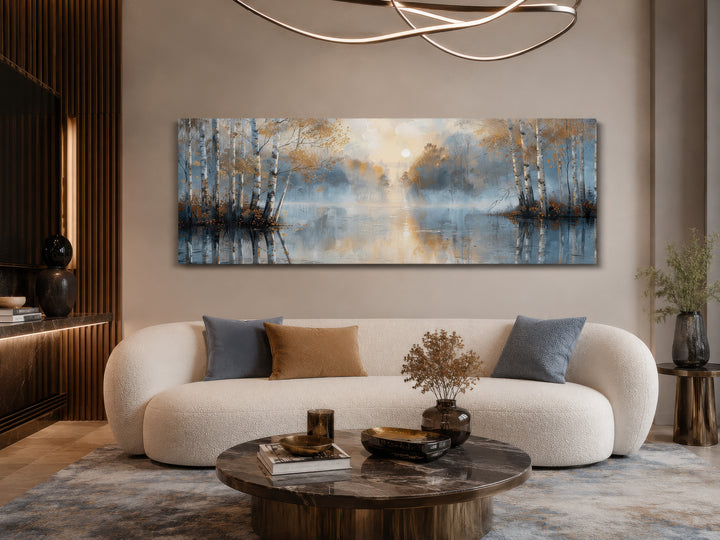 Panoramic wall art of silver birch trees in a misty forest above a modern white curved sofa.