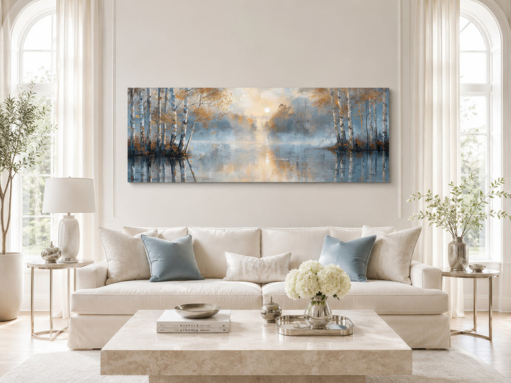Long narrow horizontal wall art of a misty silver birch tree forest over a living room sofa.