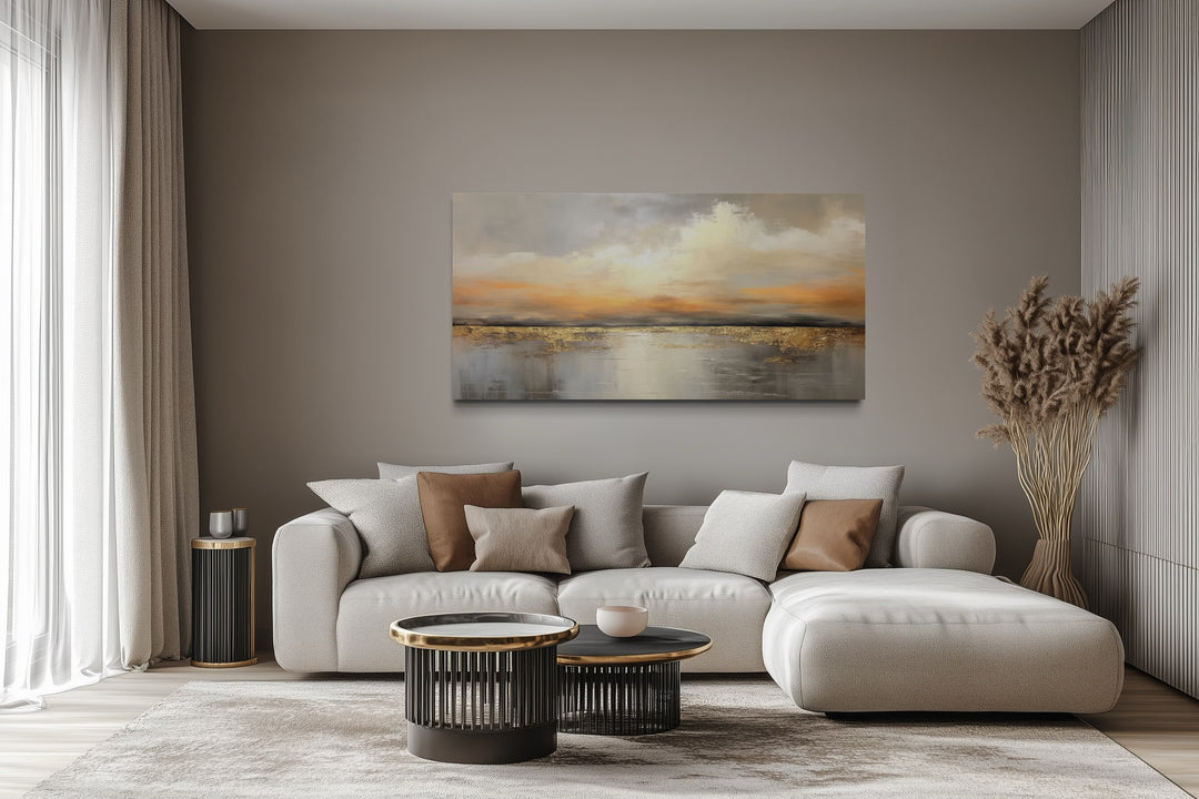Silver and gold abstract ocean sunset framed canvas wall art hanging above a modern sofa.