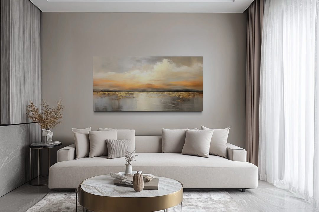 Silver and gold abstract ocean sunset framed canvas wall art hanging above a modern sofa.