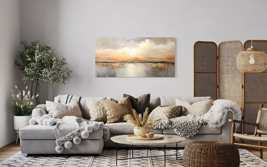 Silver Gold Abstract Ocean Sunset Framed Canvas Wall Art hanging above a grey sectional sofa.