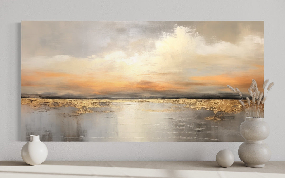 Silver and gold abstract ocean sunset framed canvas wall art above a console with ceramic vases.