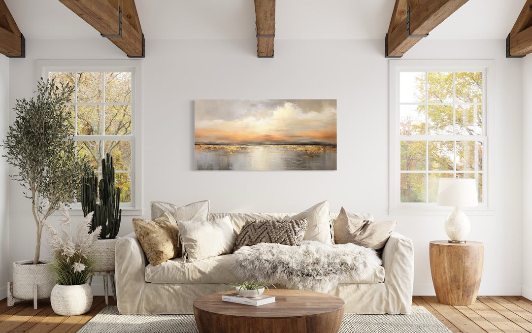 Silver and gold abstract ocean sunset framed canvas wall art hanging above a beige sofa.
