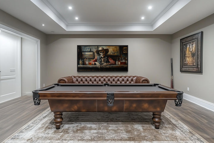 Skeleton cowboy barman framed canvas wall art hanging in a game room above a pool table and sofa.