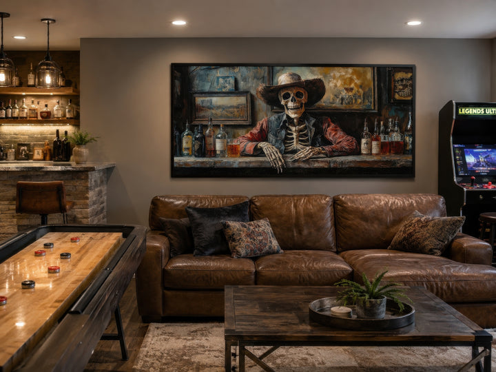 Skeleton cowboy barman framed canvas wall art hanging above a leather sofa in a rustic home bar.