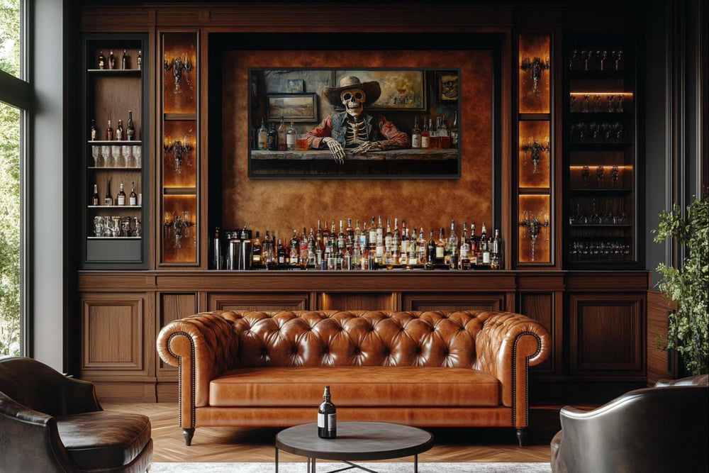 Framed canvas wall art of a skeleton cowboy barman in a saloon, hung above a leather sofa in a bar.