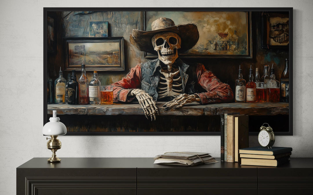 Framed canvas art of a skeleton cowboy barman at a rustic saloon bar with whiskey bottles.