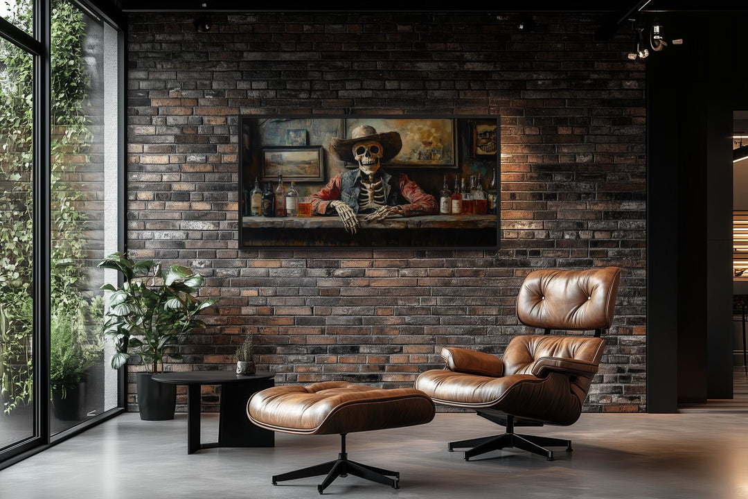 Skeleton cowboy barman framed canvas wall art on a brick wall above a leather lounge chair.