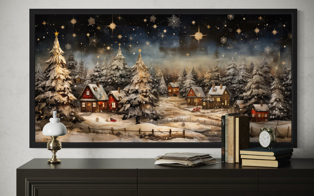 Framed wall art of a snow-covered winter village at night with glowing cottages and starry sky.