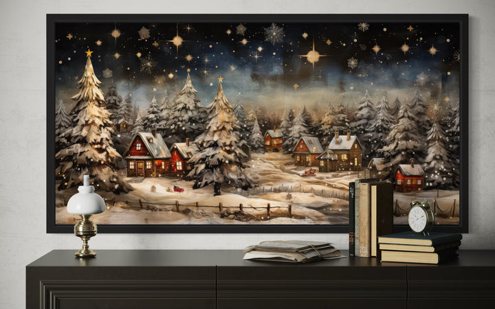 Framed wall art of a snow-covered winter village at night with glowing cottages and starry sky.