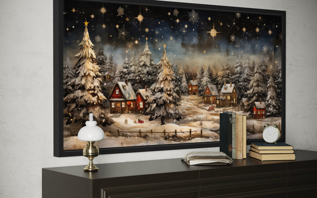 Framed wall art of a snow-covered winter village at night with glowing cottages and starry sky.