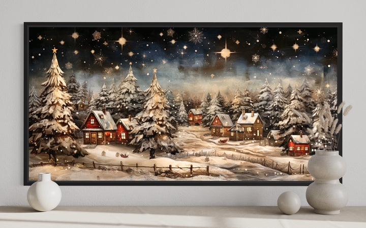 Snowy winter village at night wall art with red cottages and stars above a fireplace mantel.