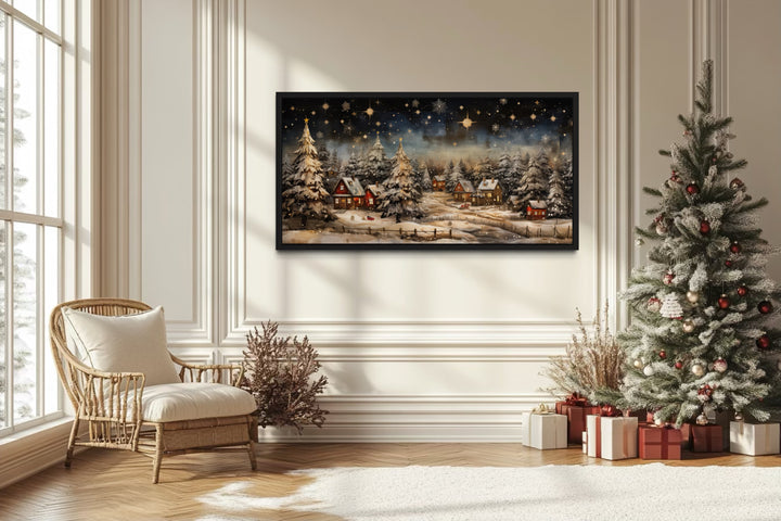 Snow-covered winter village at night wall art in a black frame above a fireplace mantel.