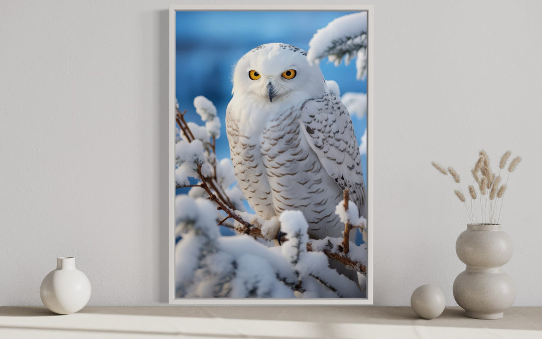 Framed canvas wall art of a snowy owl perched on snow-covered branches in a winter landscape.