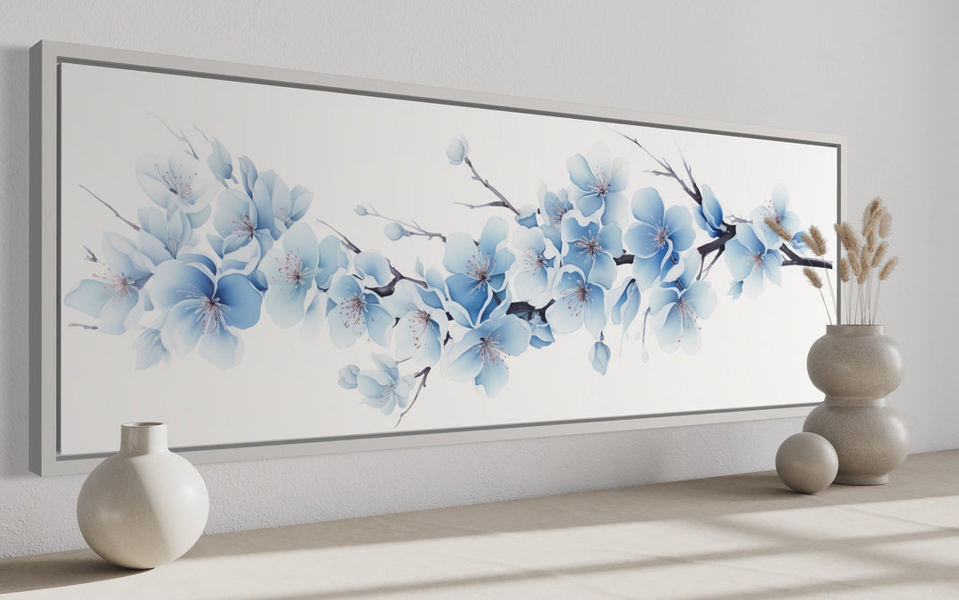 Long horizontal wall art featuring soft blue blossom flowers on a white background in a grey frame.