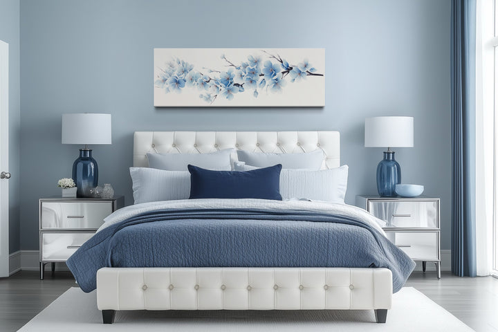 Soft blue blossom flowers long horizontal canvas wall art hanging above a white tufted bed.