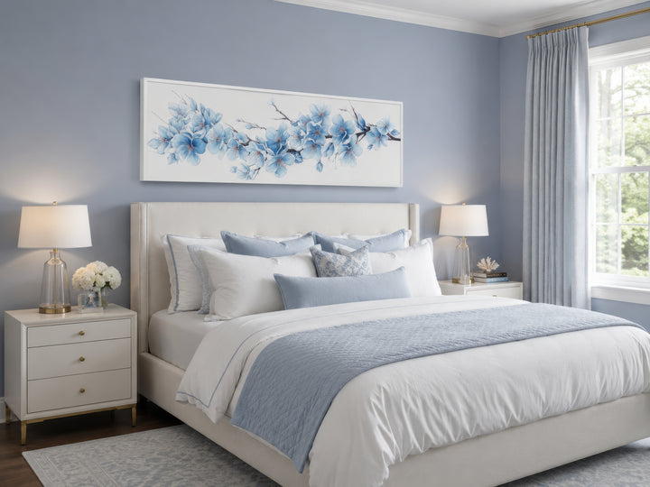 Long horizontal wall art with soft blue blossom flowers hanging above a bed in a blue bedroom.