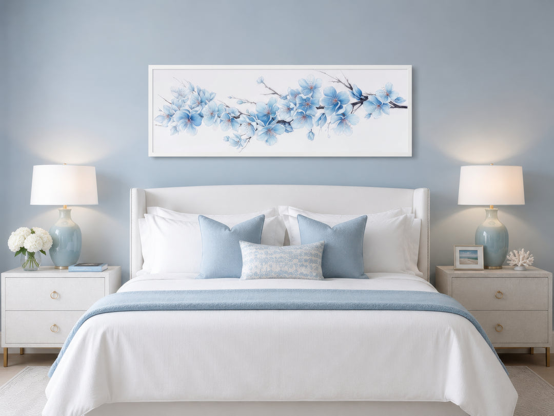 Soft blue blossom flowers long horizontal wall art hanging above a white bed in a blue bedroom.